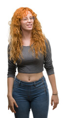 Young redhead woman winking looking at the camera with sexy expression, cheerful and happy face. - obrazy, fototapety, plakaty