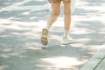 A woman is running on a sidewalk with her feet in the air