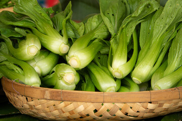 A basket full of green vegetables, including broccoli. The basket is filled with many pieces of broccoli, some of which are cut in half. The vegetables are fresh and healthy, and they look delicious