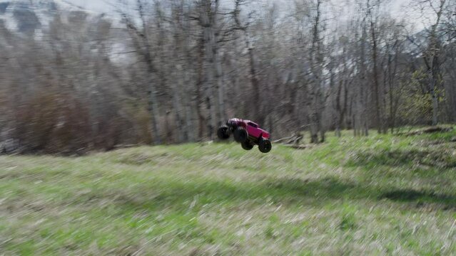 Pink RC car driving through grassy field - slow motion shot