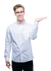 Young handsome blond man smiling cheerful presenting and pointing with palm of hand looking at the camera.