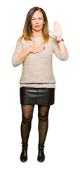 Beautiful middle age woman wearing fashion sweater Swearing with hand on chest and open palm,...