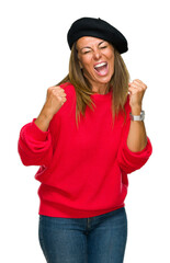 Middle age adult woman wearing fashion beret over isolated background very happy and excited doing winner gesture with arms raised, smiling and screaming for success. Celebration concept.