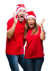 Middle age hispanic couple wearing christmas hat over isolated background celebrating crazy and amazed for success with arms raised and open eyes screaming excited. Winner concept