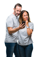 Naklejka premium Middle age hispanic couple texting message on smartphone ver isolated background serious face thinking about question, very confused idea