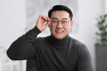 Portrait of smiling businessman in glasses indoors