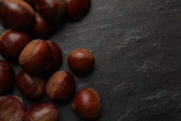 Roasted edible sweet chestnuts on grey textured table, flat lay. Space for text