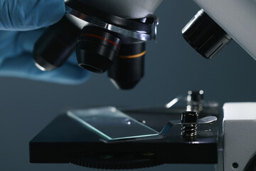 Scientist working with microscope on dark background, closeup