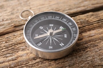 Fototapeta na wymiar One compass on wooden table, closeup. Tourist equipment
