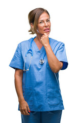 Middle age senior nurse doctor woman over isolated background looking confident at the camera with smile with crossed arms and hand raised on chin. Thinking positive.