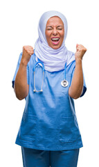 Middle age senior arab nurse woman wearing hijab over isolated background very happy and excited doing winner gesture with arms raised, smiling and screaming for success. Celebration concept.