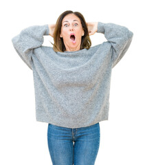 Beautiful middle age woman wearing winter sweater over isolated background Crazy and scared with...