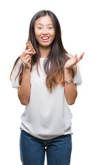 Fototapeta na wymiar Young asian woman eating chocolate energetic bar over isolated background very happy and excited, winner expression celebrating victory screaming with big smile and raised hands