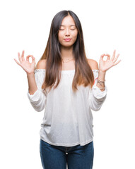 Young asian woman over isolated background relax and smiling with eyes closed doing meditation gesture with fingers. Yoga concept.