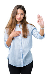 Young beautiful brunette business woman over isolated background Swearing with hand on chest and...
