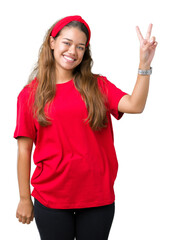 Obraz na płótnie Canvas Young beautiful brunette woman wearing red t-shirt over isolated background smiling with happy face winking at the camera doing victory sign. Number two.