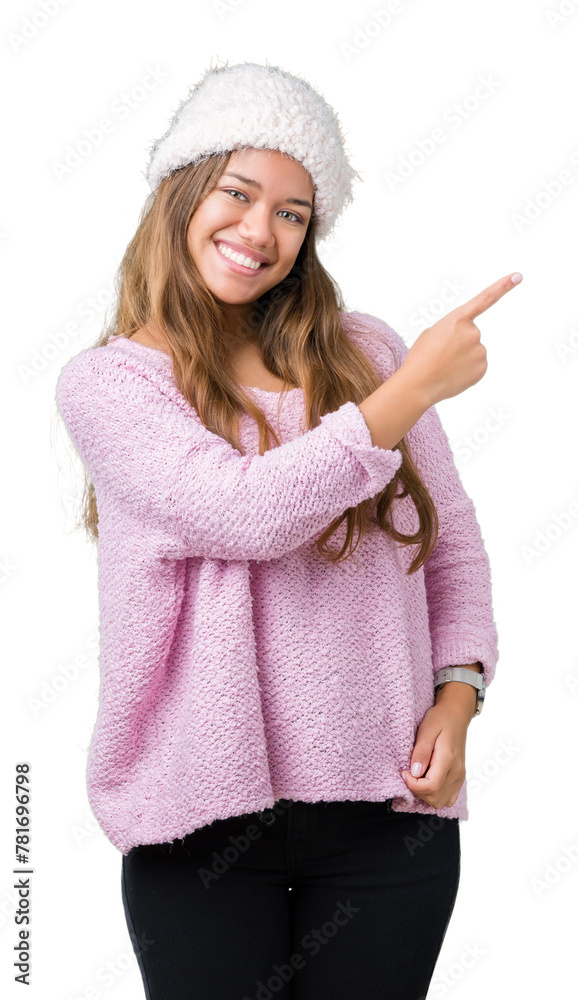 Sticker Young beautiful brunette woman wearing sweater and winter hat over isolated background cheerful with a smile of face pointing with hand and finger up to the side.