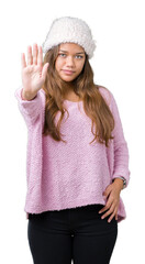 Fototapeta na wymiar Young beautiful brunette woman wearing sweater and winter hat over isolated background doing stop sing with palm of the hand. Warning expression with negative and serious gesture on the face.