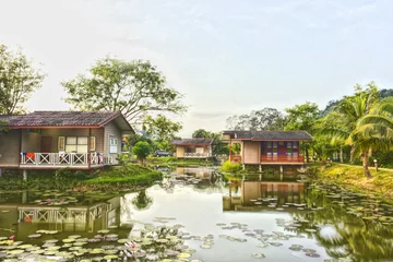 Foto op Canvas Baan Rim Nam. Beautiful landscape view of three house wooden with reflect shadow on water pond isolated with green nature background. Home traditional design for create to help cool down in summer. © Taweesak