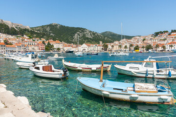 Fototapeta na wymiar Boats at tied up in harbour with picturesque waterfront and town across bay Croatia