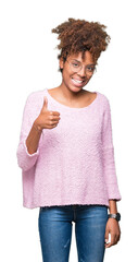 Beautiful young african american woman wearing glasses over isolated background doing happy thumbs up gesture with hand. Approving expression looking at the camera showing success.