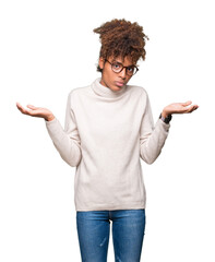 Beautiful young african american woman wearing glasses over isolated background clueless and...