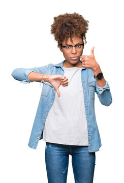 Beautiful young african american woman wearing glasses over isolated background Doing thumbs up and down, disagreement and agreement expression. Crazy conflict