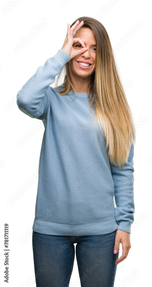 Sticker Beautiful young woman wearing sweater and jeans with happy face smiling doing ok sign with hand on eye looking through fingers