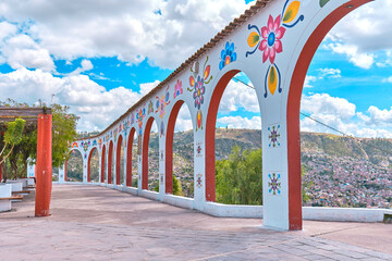 A long white archway with trees on either side, arch of Acuchimay, Ayacucho. Peru