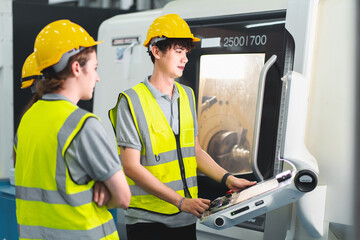 Professional engineering or technician team work on PLC Control panel CNC machine to control the efficiency of robotic machinery. Expertise helping to maintenance, programming, and improving equipment