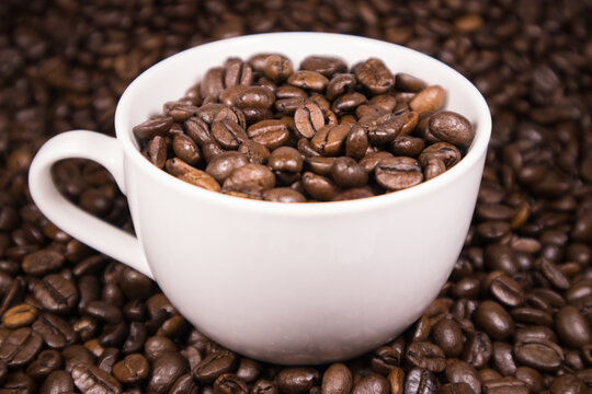 Kawowy aromat w białej filiżance na tle rozsypanej kawy