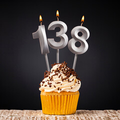 Birthday candle number 138 - Anniversary cupcake on black background