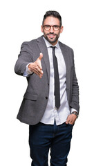 Young handsome business man over isolated background smiling friendly offering handshake as greeting and welcoming. Successful business.
