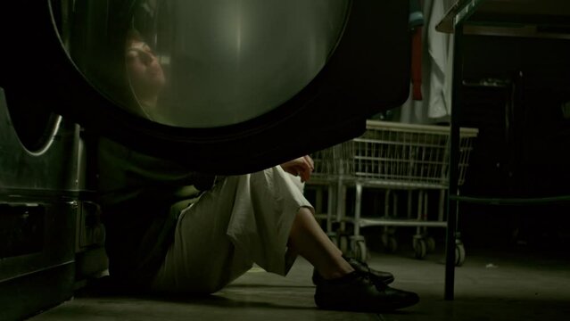 Reflexiones en la oscuridad: Mujer solitaria en la lavandería.