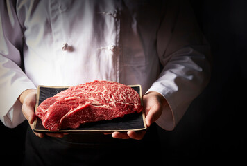 Chef holding fresh raw meat on plate