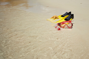 Yellow flippers, snorkel set and starfish on the beach