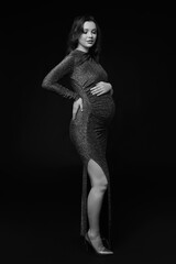 Black and white portrait of pregnant female in sequin dress with hands near pregnant belly. - 781725773