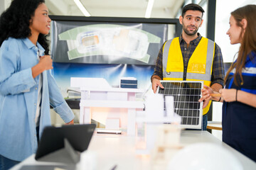 Focused construction specialists evaluate a solar energy panel model in a modern workspace with...