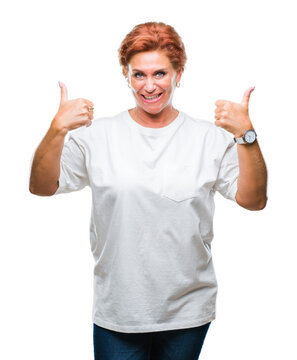 Atrractive senior caucasian redhead woman over isolated background success sign doing positive gesture with hand, thumbs up smiling and happy. Looking at the camera with cheerful expression.