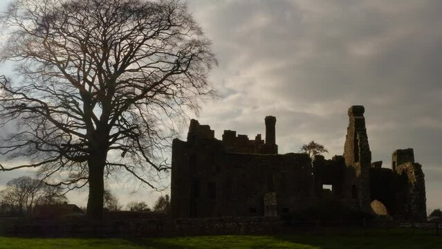 Establishing shot of Bective Abbey, low orbit backlit by sun with building silhouette of Irish heritage