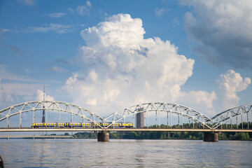 Panorama of the Daugava river in Riga, latvia, with a train from Latvian railways over dzelzcela tilts or Riga Railway Bridge with a skyline of business skyscrapers in background with high rise towers
