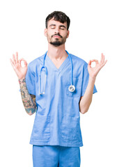 Young handsome nurse man wearing surgeon uniform over isolated background relax and smiling with eyes closed doing meditation gesture with fingers. Yoga concept.