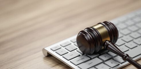 Gavel at the computer keyboard: Legal and law concept. Wooden hammer of justice and order - 781745319
