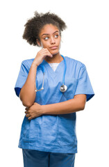 Young afro american doctor woman over isolated background with hand on chin thinking about question, pensive expression. Smiling with thoughtful face. Doubt concept.