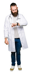 Young blond doctor man with beard wearing medical coat Checking the time on wrist watch, relaxed and confident