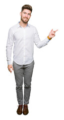 Young handsome business man with a big smile on face, pointing with hand and finger to the side looking at the camera.