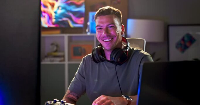 Happy man, face and gamer at night with headphones, reflection and neon screen for live streaming. Person, excited and portrait with gaming technology and confident in esports competition on internet