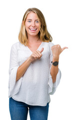 Obraz premium Beautiful young elegant woman over isolated background Pointing to the back behind with hand and thumbs up, smiling confident