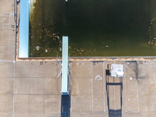 Drone view of an empty and drained winterized swimming pool above the diving board.