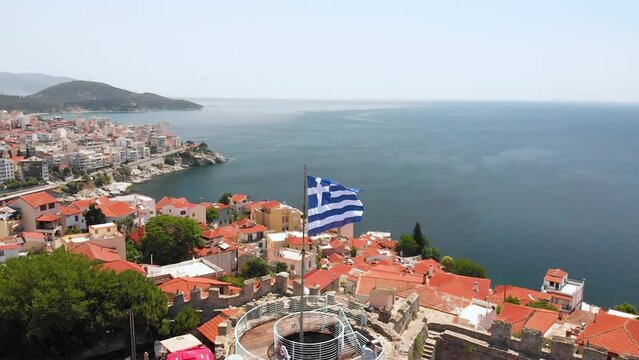 Aerial Pull Back Shot of Kavala Old Town Greece and Fortress, Greek Flag Waving on Top of Tower in the Castle